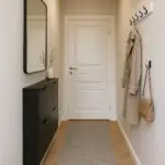 Narrow hallway with light-colored walls, mirror, and shoe storage alt="Small hallway design with mirror and wall-mounted shoe cabinet"