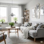 A cozy Scandinavian-style living room featuring a light gray sofa with geometric cushions, a wooden coffee table with a plant, soft curtains, framed minimalist art, and natural light filling the space.